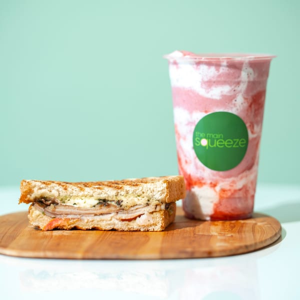 Grilled sandwich with turkey and cheese next to a strawberry smoothie from The Main Squeeze.